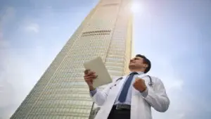 Professional sanitari davant d'un edifici com a metàfora de l'elecció d'un despatx sanitari a Barcelona